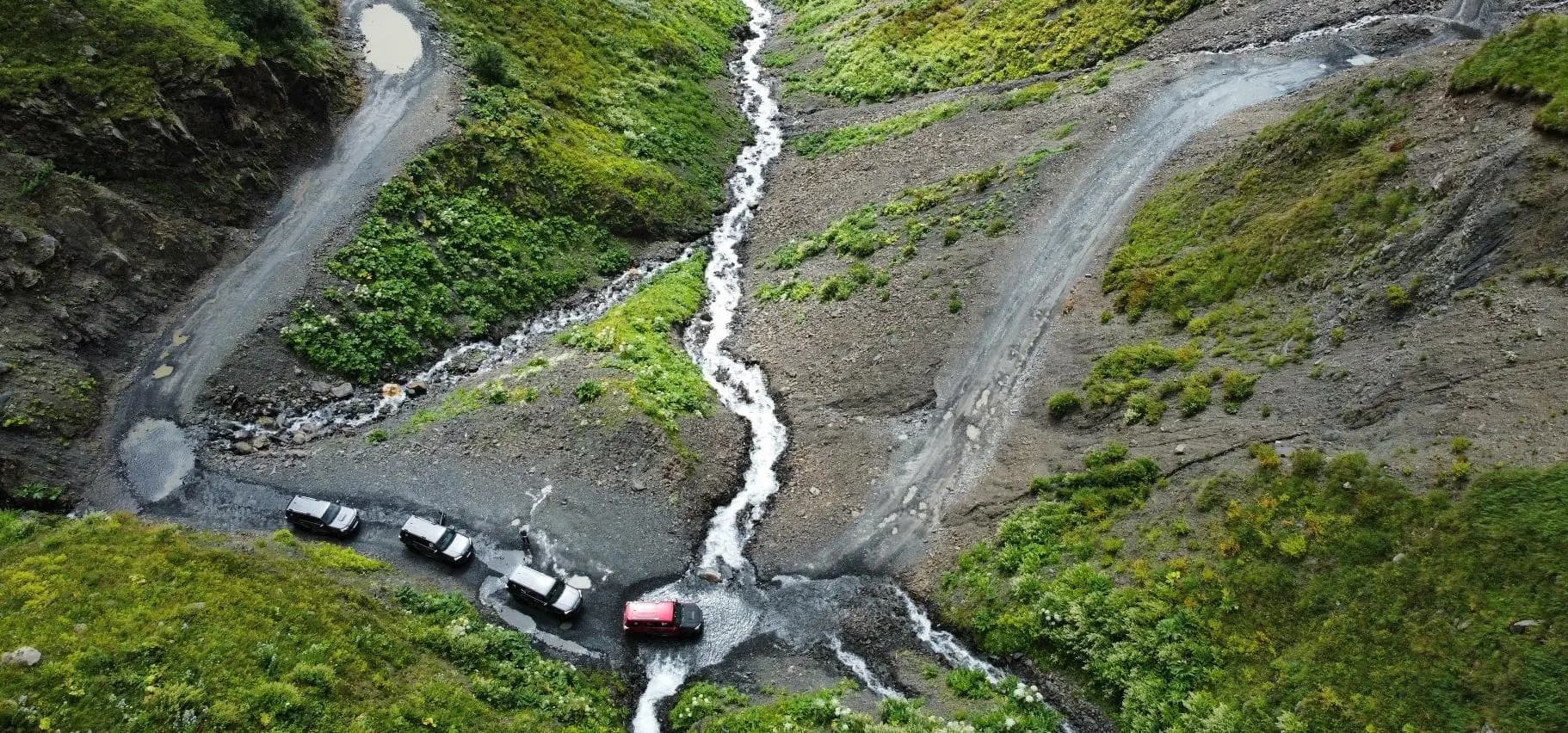 Convoy of 4WD vehicles crossing a Georgian mountain river