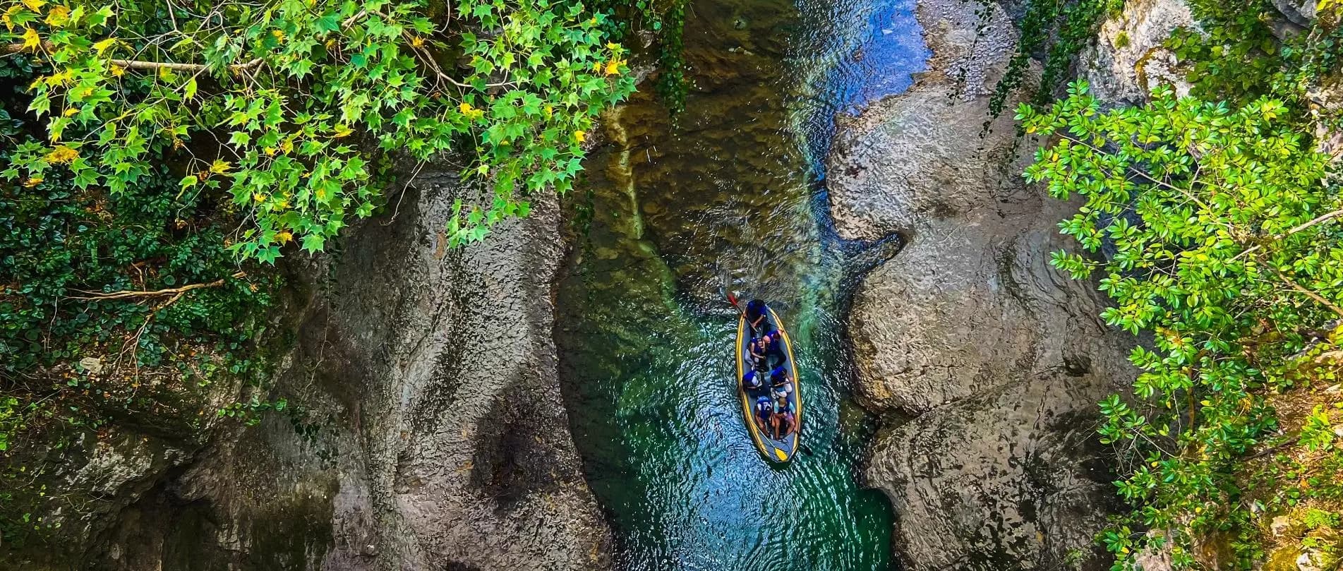 Small boat travelling through a narrow green canyon in Georgia